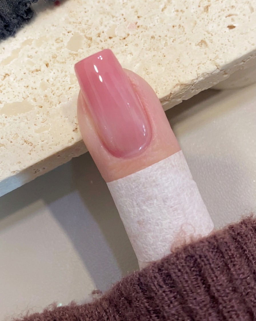 ピーチオンブレネイルの仕上げに、透明な高光沢トップコートを塗っている様子。