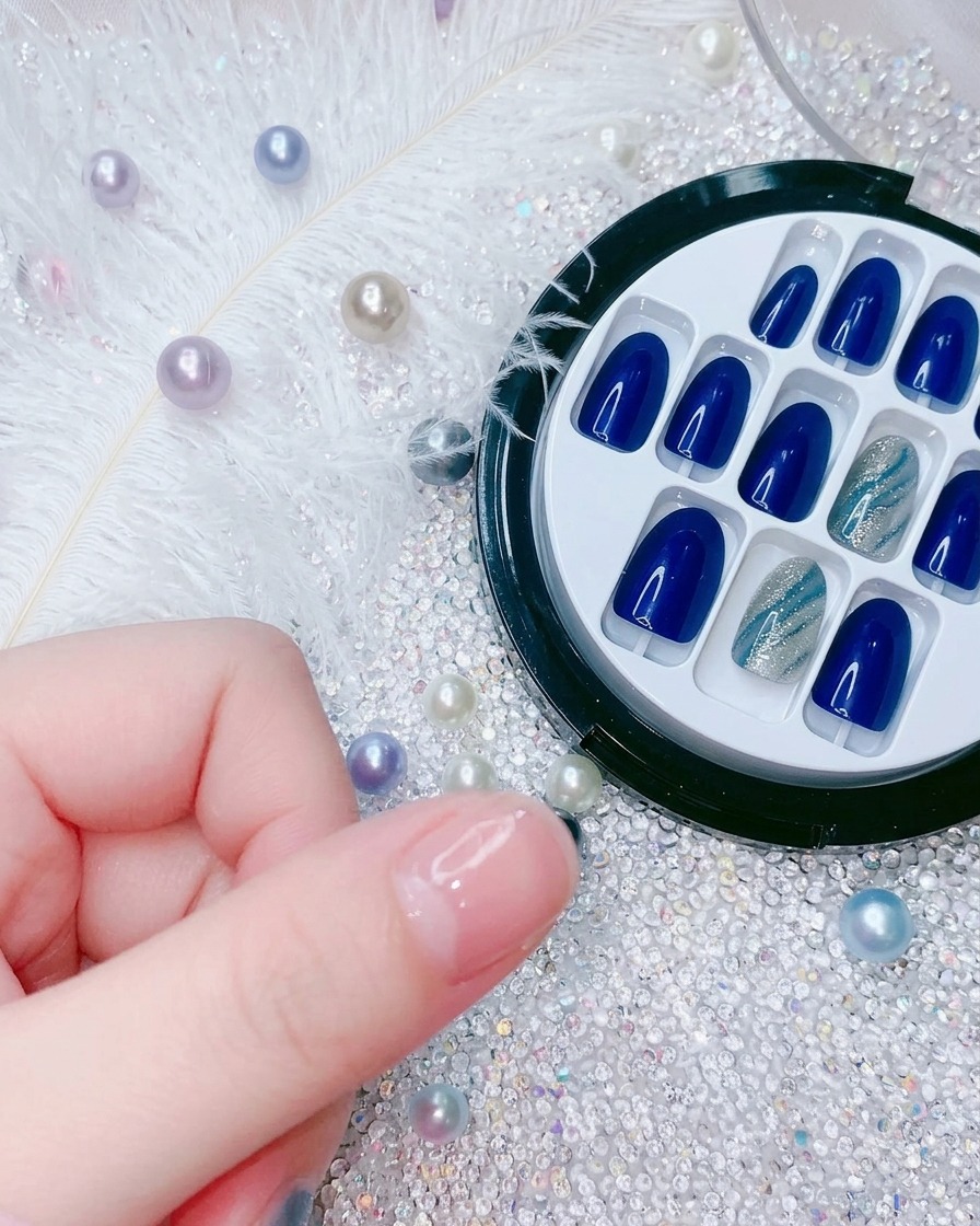 人差し指に新しいエレクトリックブルーのプレスオンネイルを配置しようとしている写真。