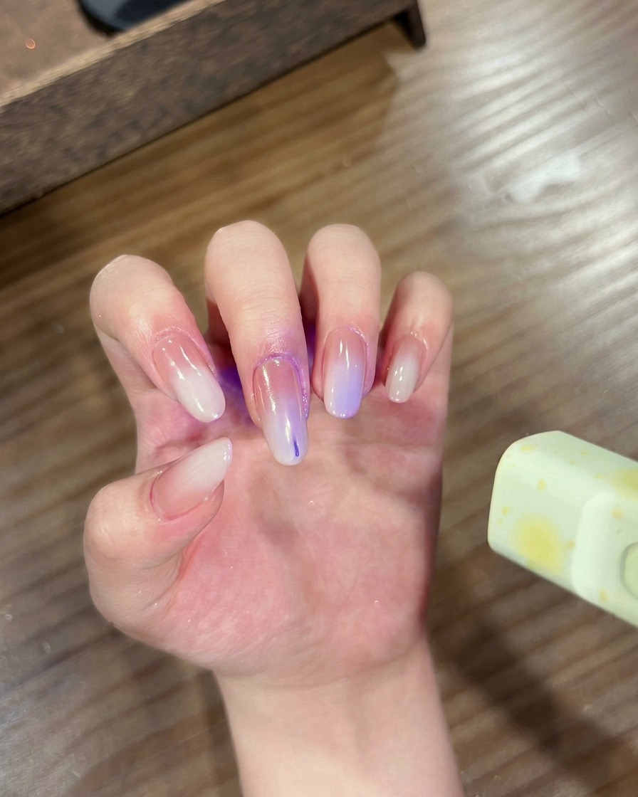 グラデーションクロムネイルの指先をUV/LEDライトに入れて硬化させている手。