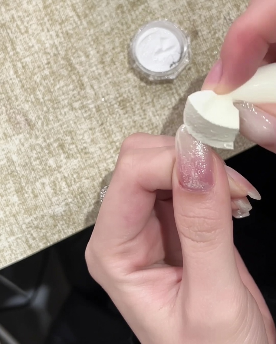 ゴールドミラーを乗せたネイルに、最後の仕上げでトップコートを塗っている様子。
