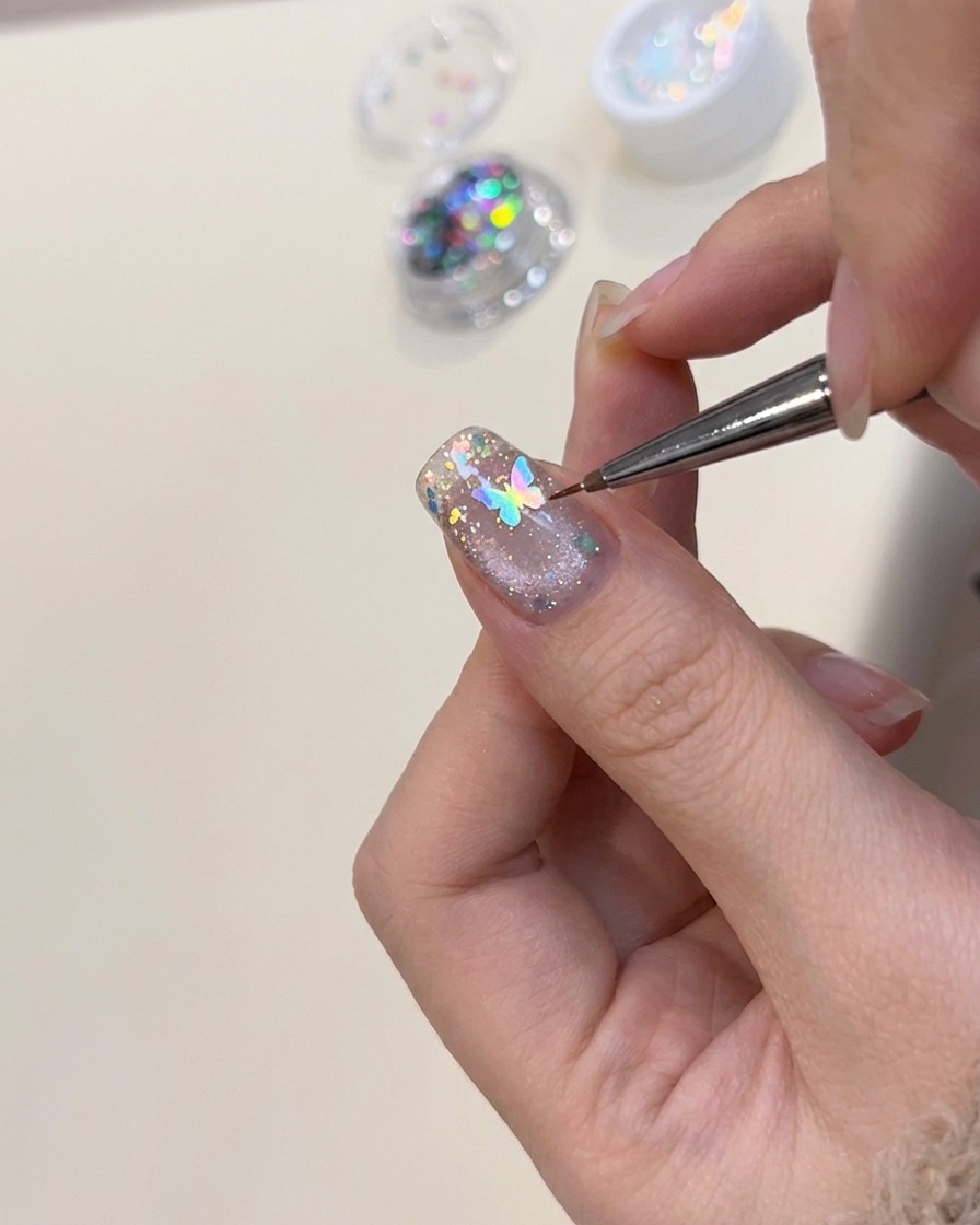 ピンセットで蝶のネイルパーツを乗せている様子