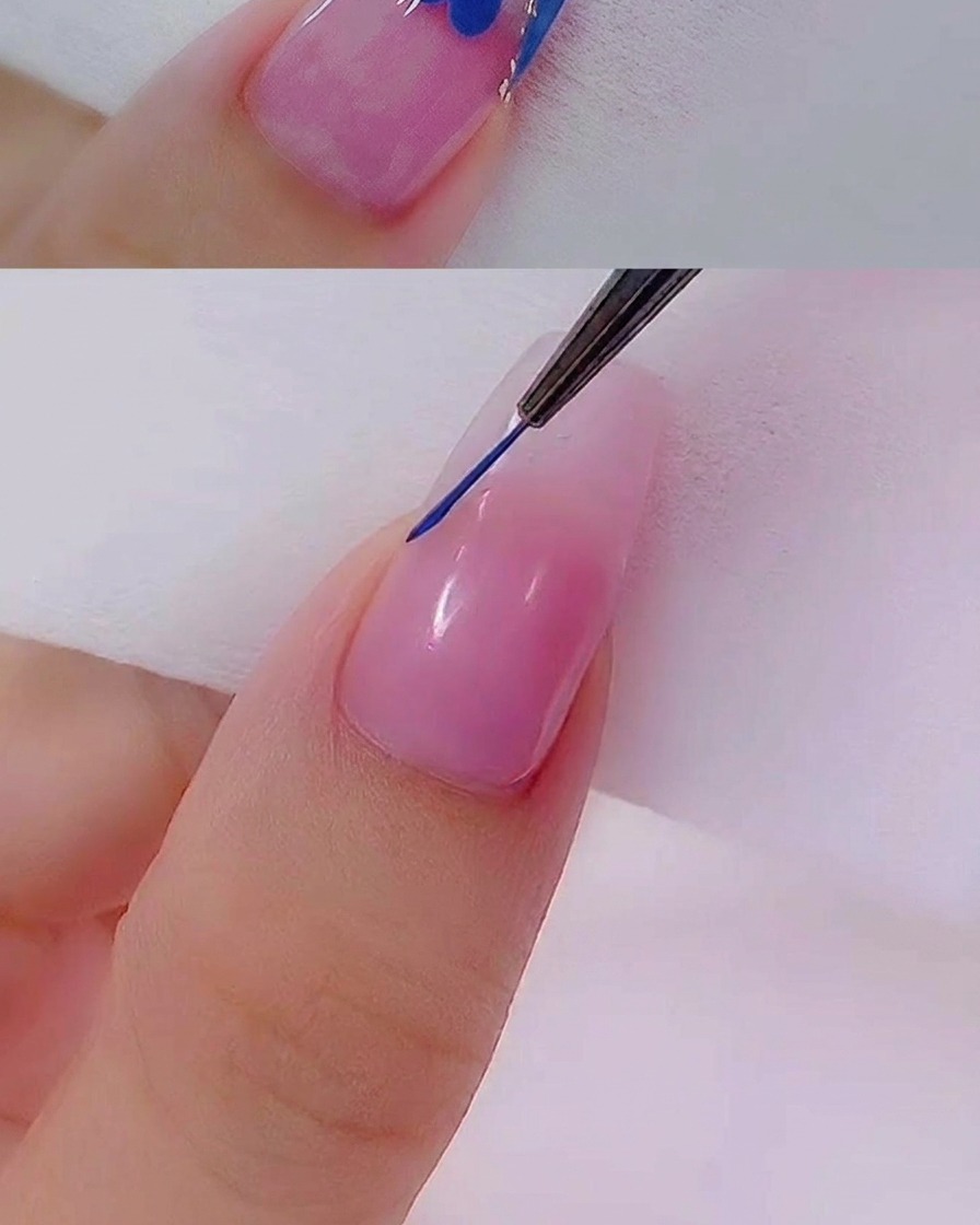 細いライナーブラシを使って、自爪風のネイルチップの先端に正確なブルーのラインを描いているクローズアップ画像。