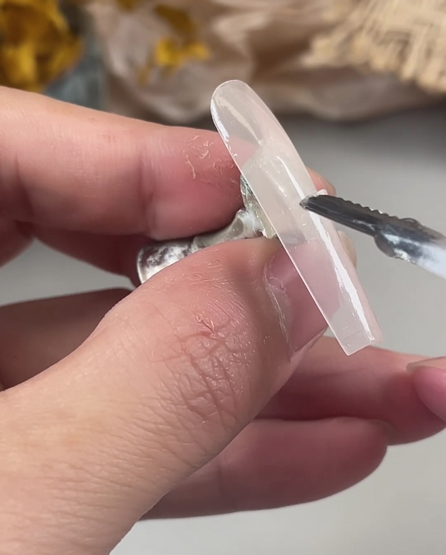 未硬化のジェル面にピンセットでオーロラホログラムのラメをのせている様子。