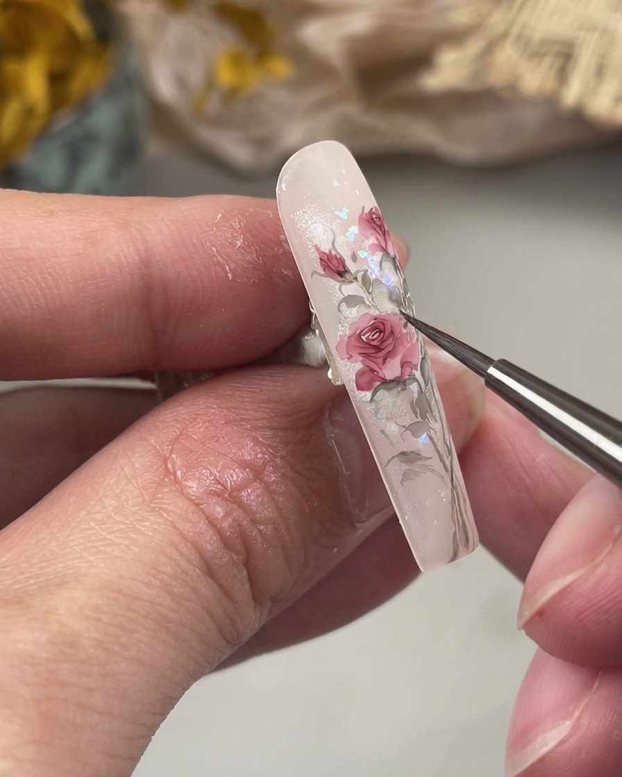 バラの根元に細いグリーンの葉を描き込んでいる様子。