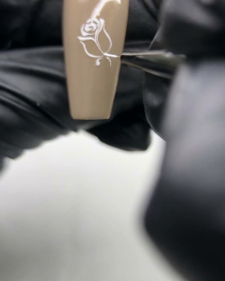 ペイントされた薔薇の茎の反対側に、ネイルブラシで繊細な葉のディテールを追加しているアップ画像。