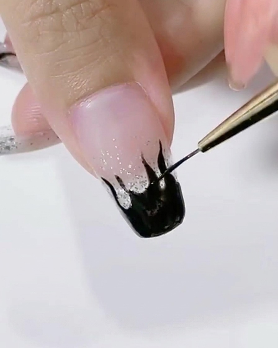 ライナーブラシで黒い炎のデザインの縁を滑らかに整えている様子
