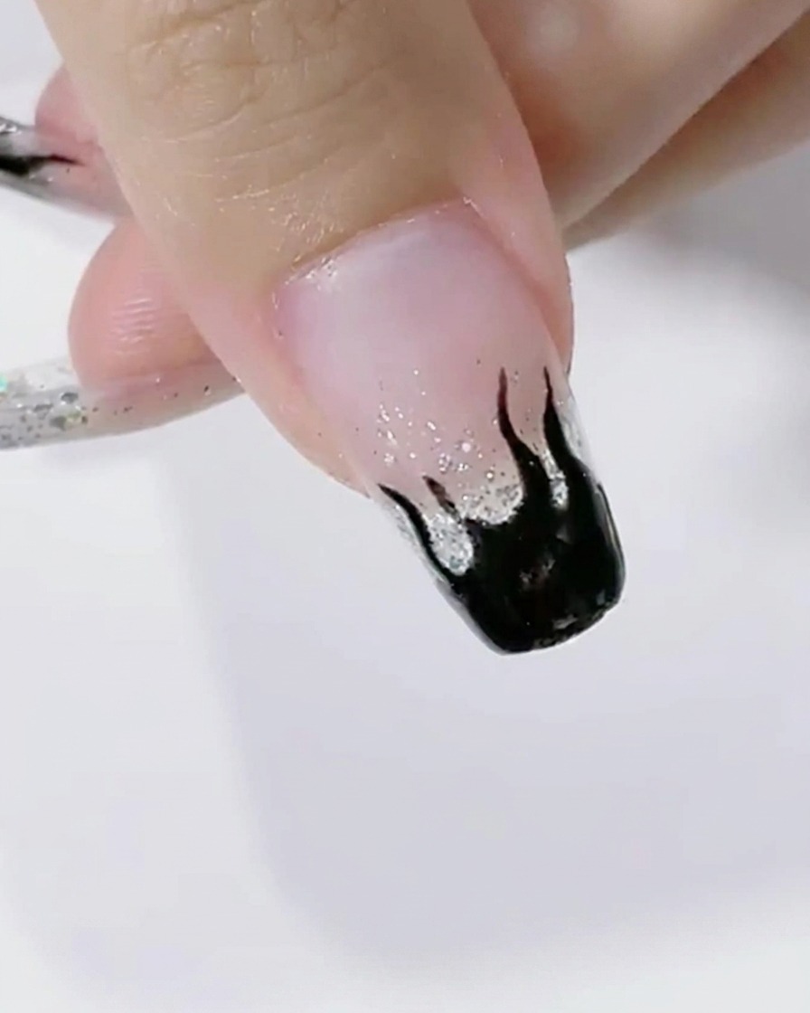 黒い炎のアートを施した爪をLEDライトで硬化している様子