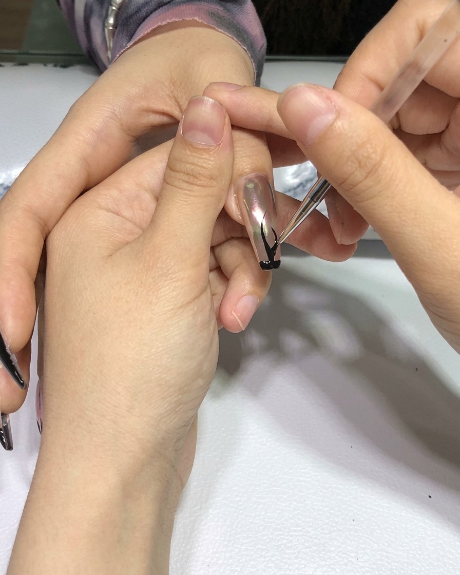 完成したブラックフレイムのネイルアートを施した手が、プロ仕様のネイル硬化ランプの中に入っている様子。