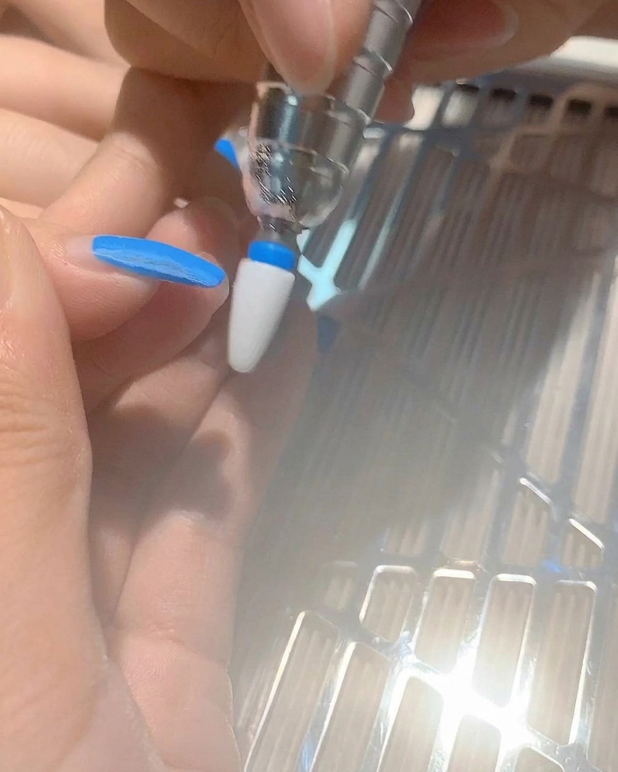 ネイルマシンを使って爪からブルーのジェルネイルを削り落とす様子