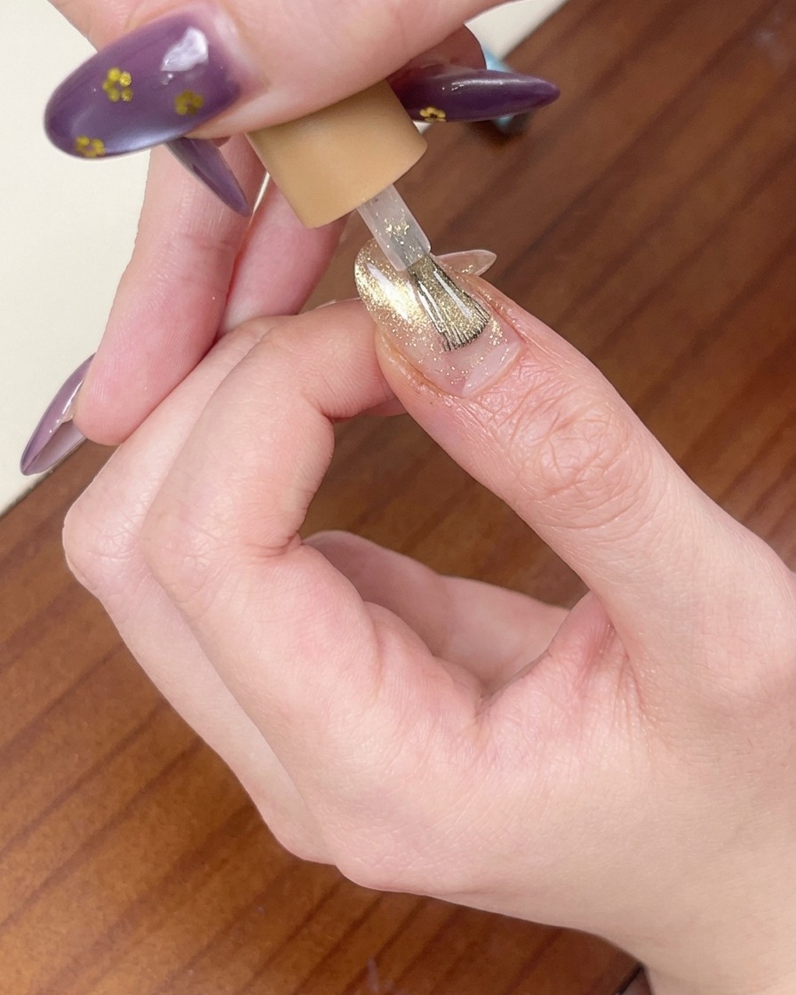 ラメ感のあるピンクゴールドのキャットアイジェルを塗っている様子。