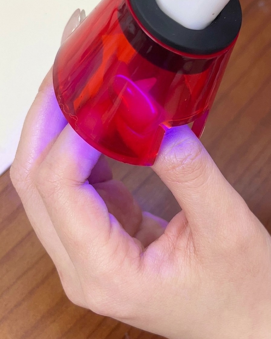 マグネットで模様を作った直後に、赤い携帯型LEDランプで硬化させている様子。