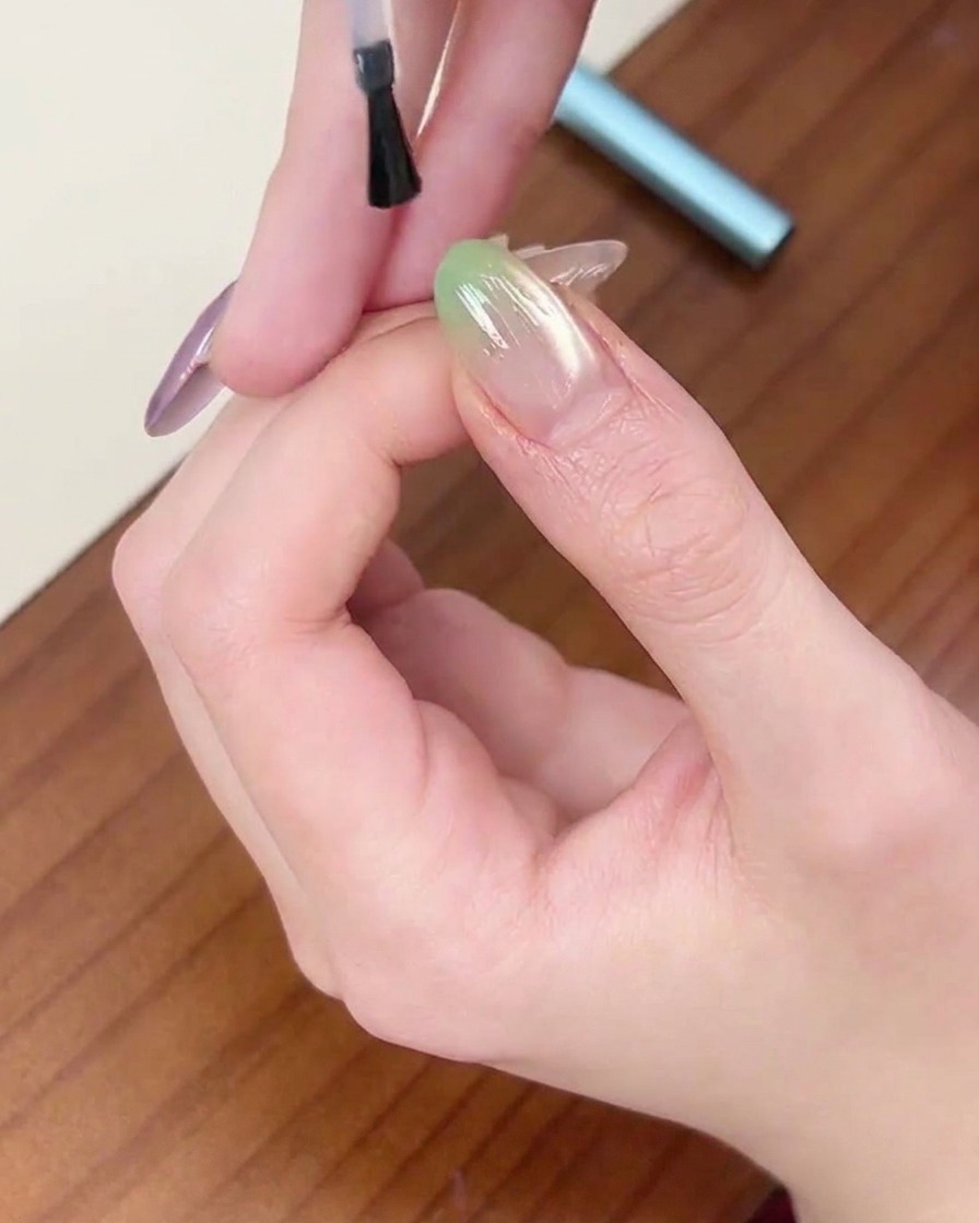 グリーンネイルの仕上げにクリアトップコートを塗っている様子。