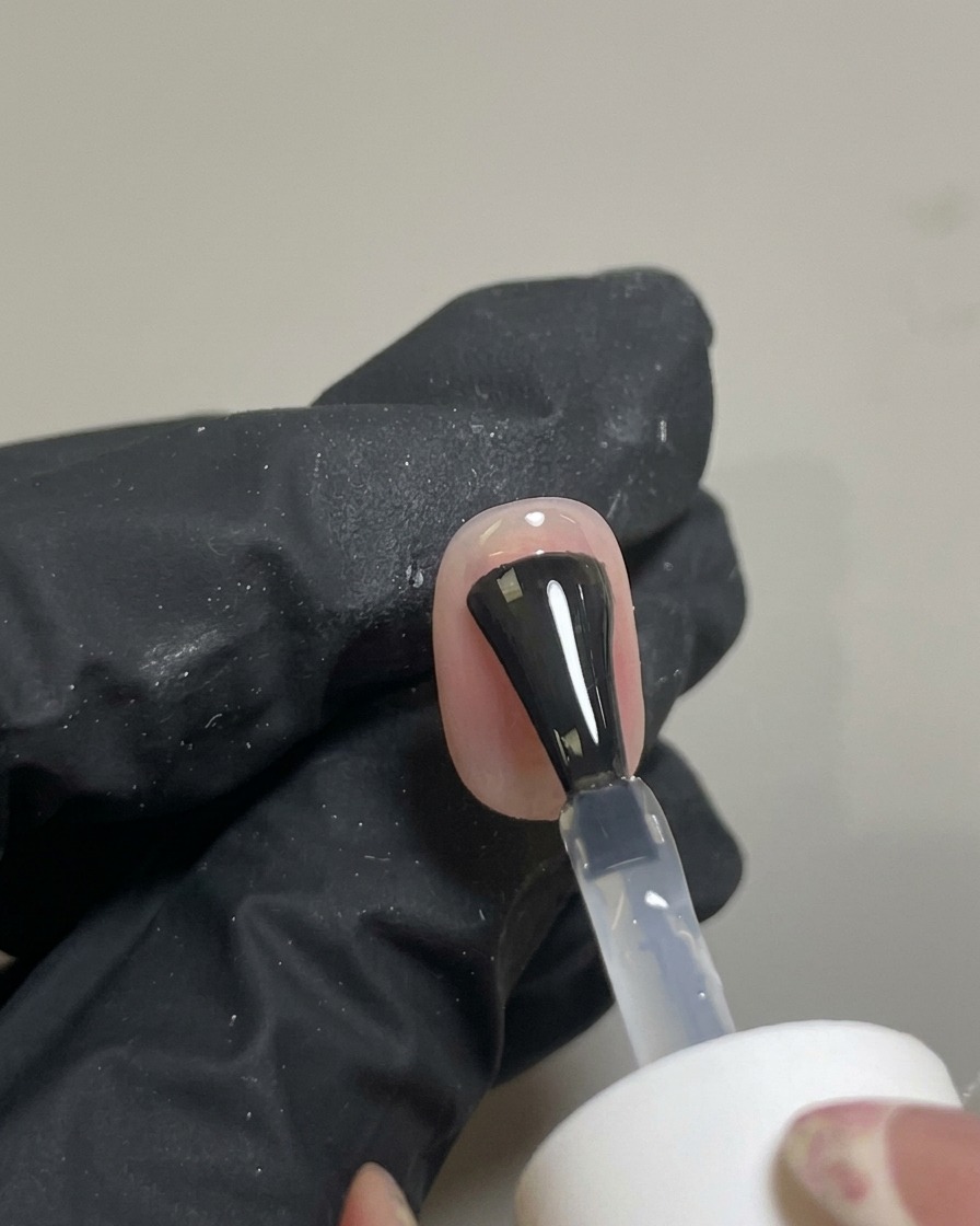 完成したチークネイルの上に、クリアで艶のあるトップコートを筆で塗っている様子