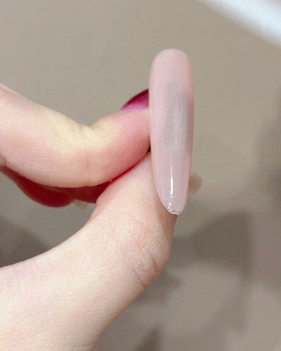 糸くずの出ないワイプで硬化したジェルネイルの表面を拭き取っている様子。