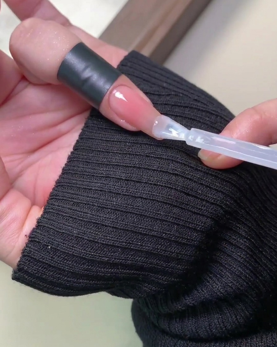 ネイルを施した手がUV/LEDランプの中に入り、光に照らされている様子。