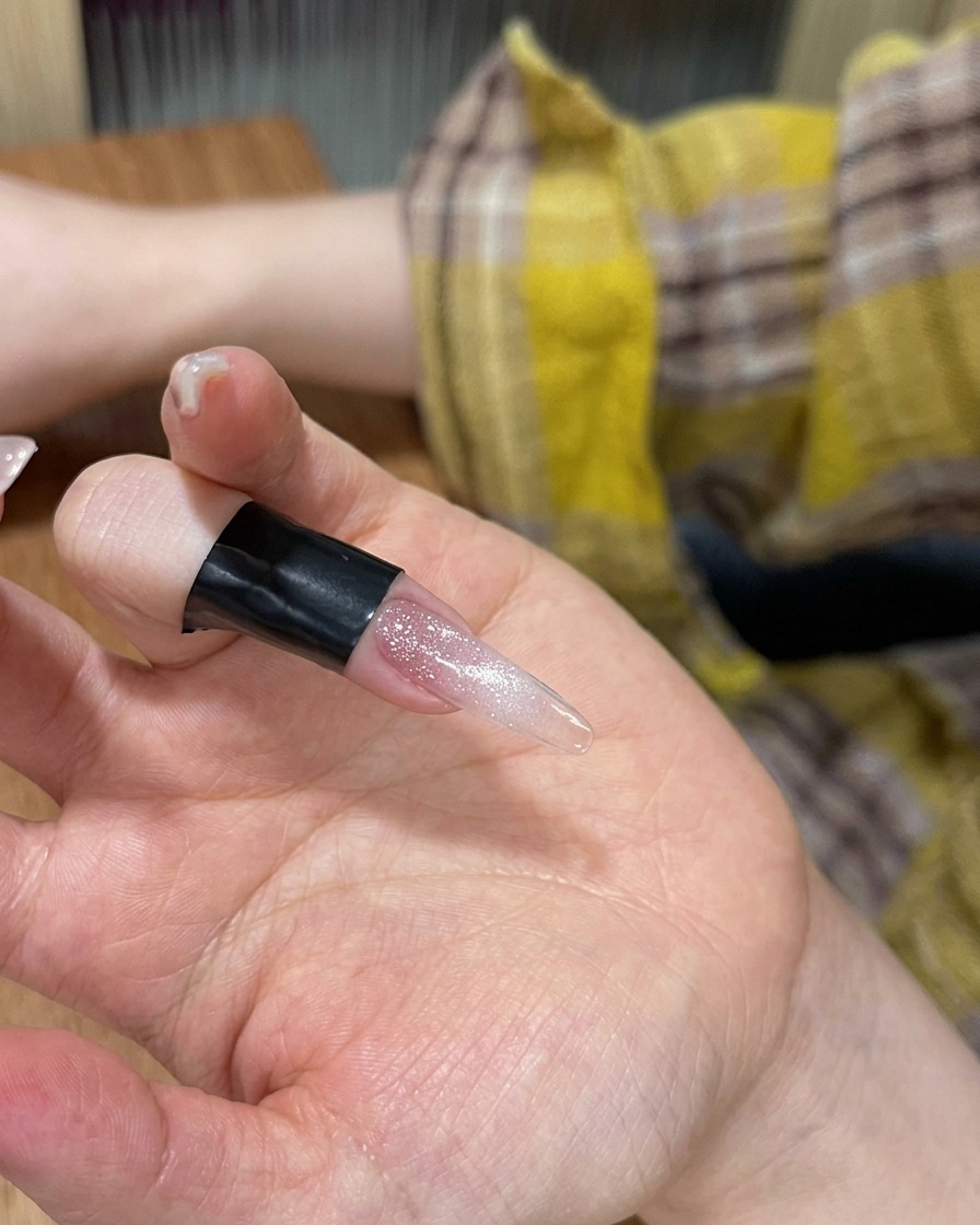 キャットアイジェルを塗った指をポータブルLEDランプに入れている様子。