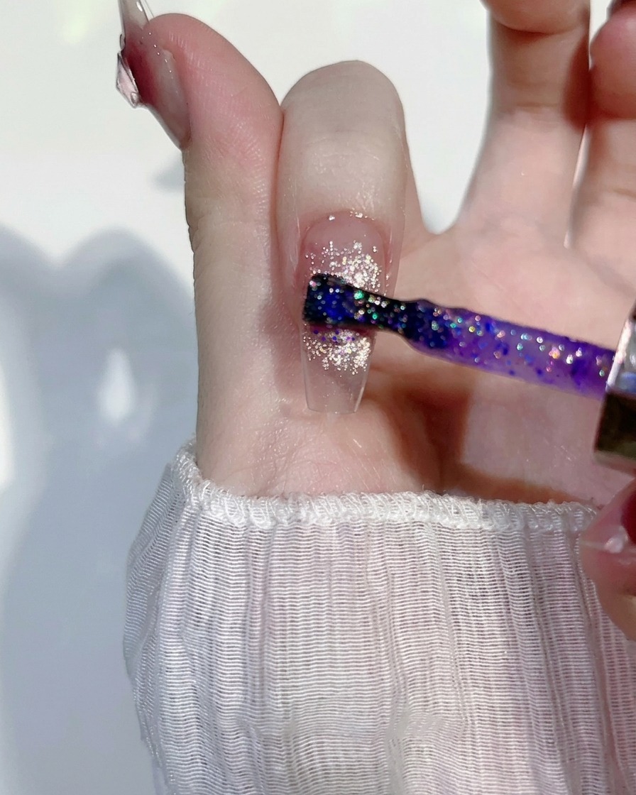 ピンクのキャッツアイネイルの上に、薄いパープルのグリッタージェルを薄く塗っている様子。