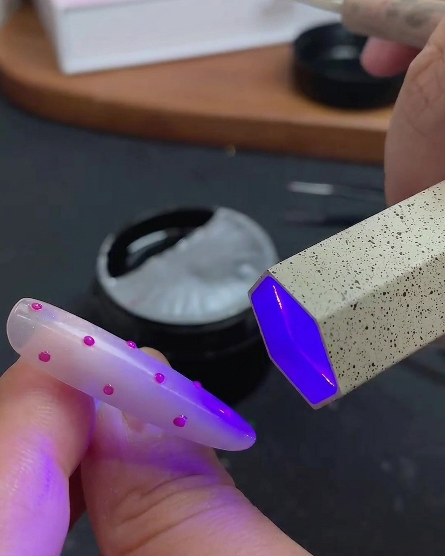 ネイル全体にクリアなトップコートを塗って仕上げている様子。