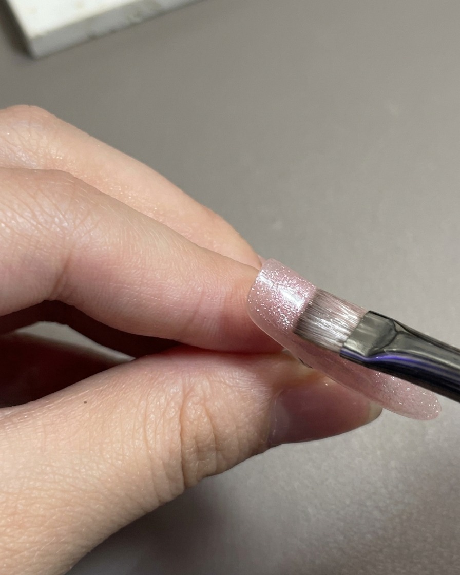 ピンクのマグネットジェルをフラットブラシで塗布している様子