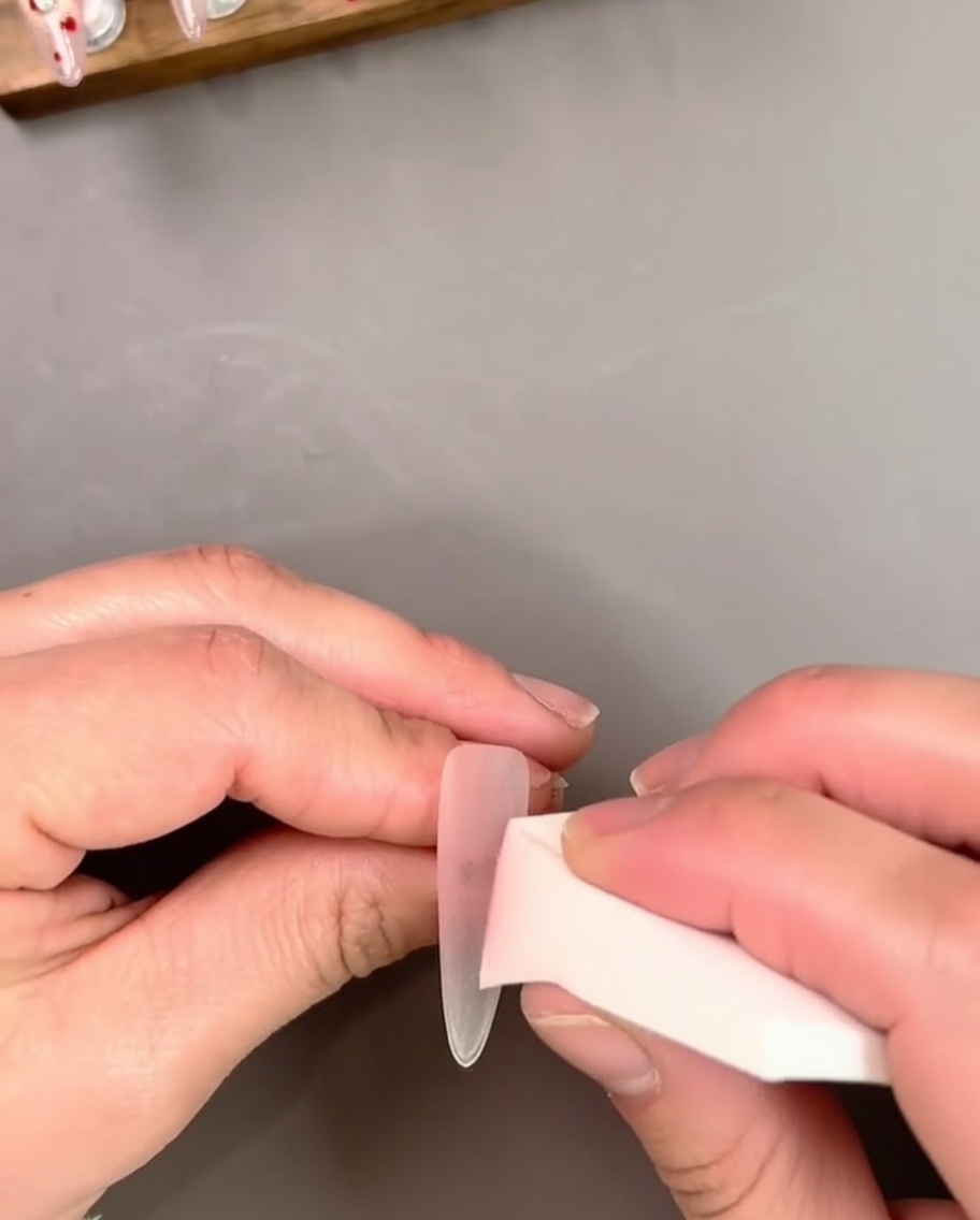 ネイルチップにシアーなピンクジェルを筆で塗っている様子