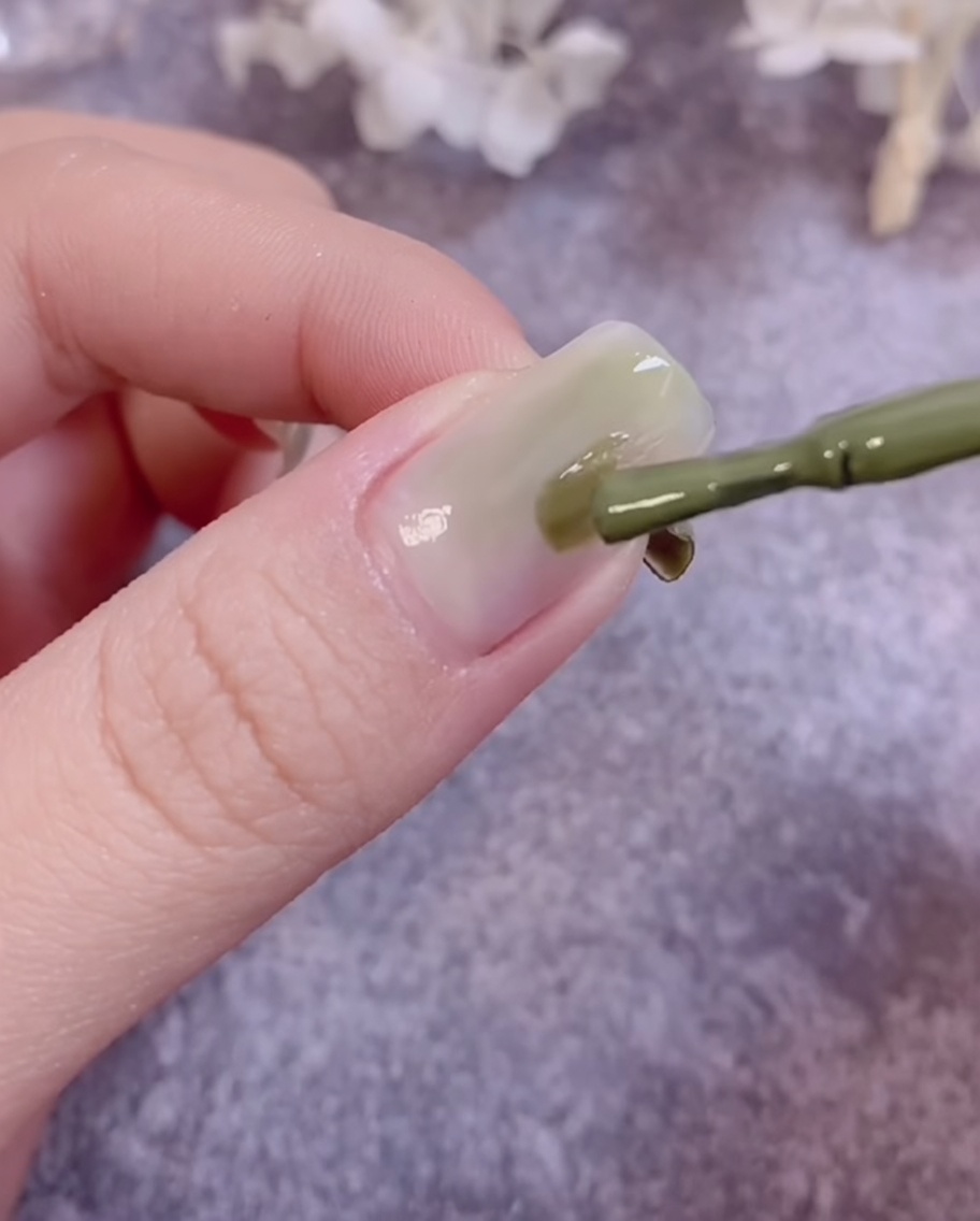 爪の表面でグリーンジェルを馴染ませ、グラデーションを作っている筆の様子。