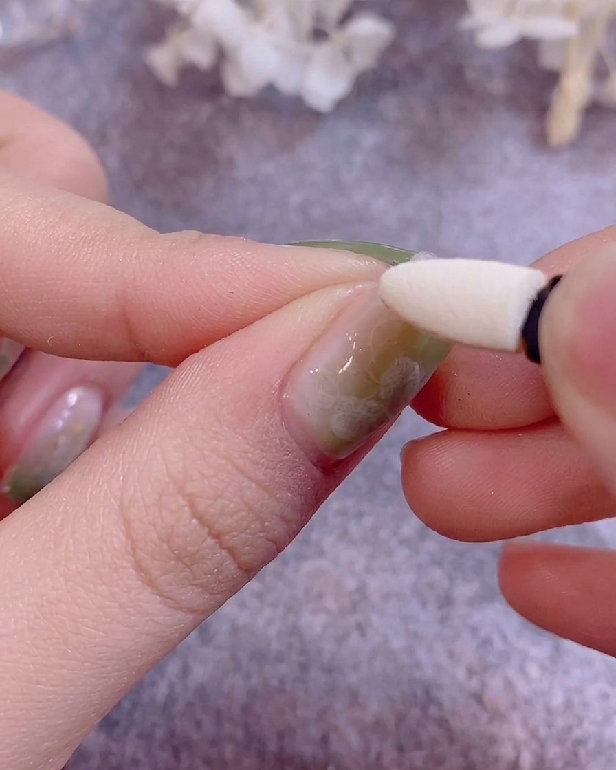 シリコンチップを使って、ジェルネイルの上にメタリックなクロムパウダーを擦り込んでいる様子。