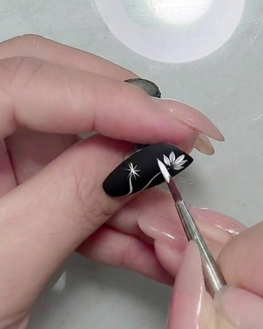 バランスよく花びらが描き足され、マットブラックの上で白いデイジーが完成している様子。
