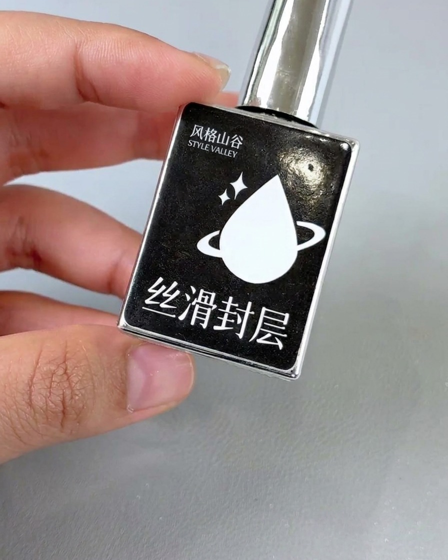 仕上がったフラワーネイルに、クリアなグロッシートップコートを塗っている様子。