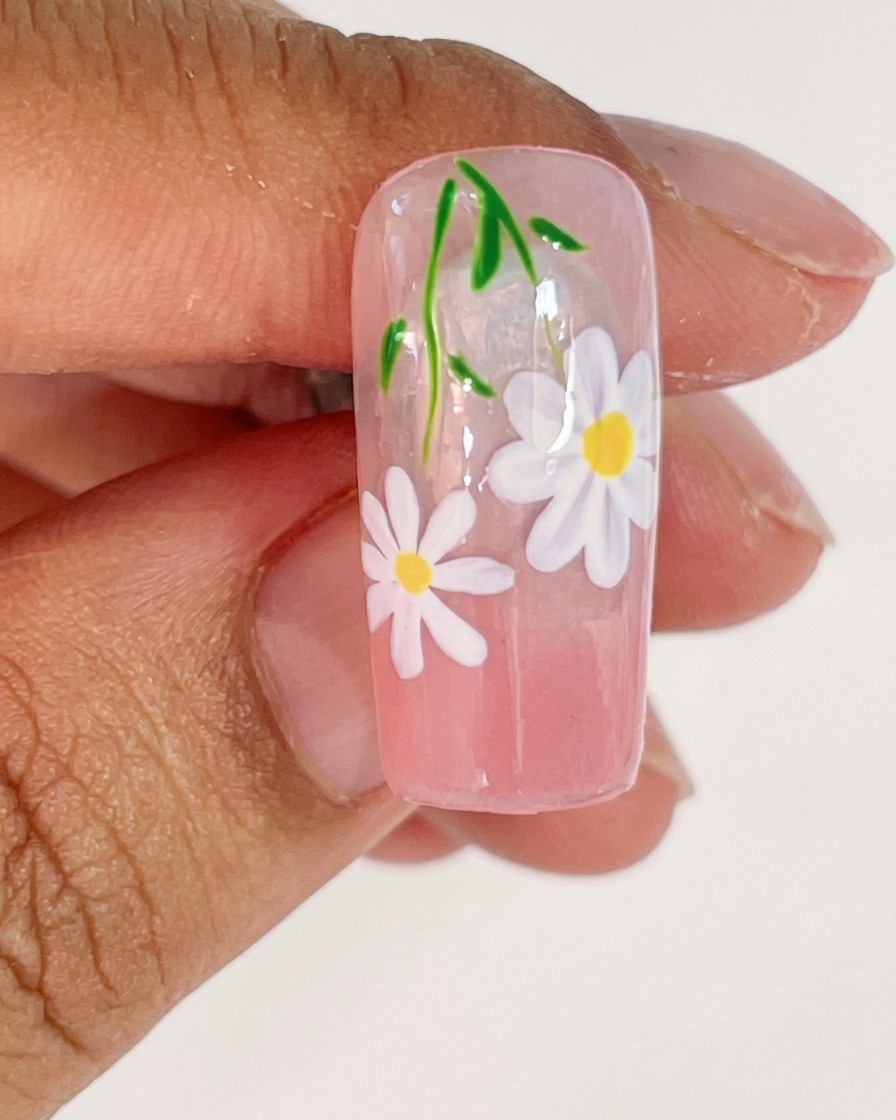 描きたてのホワイトの花びらを硬化するために、UVランプの中に入れられたネイルチップ。