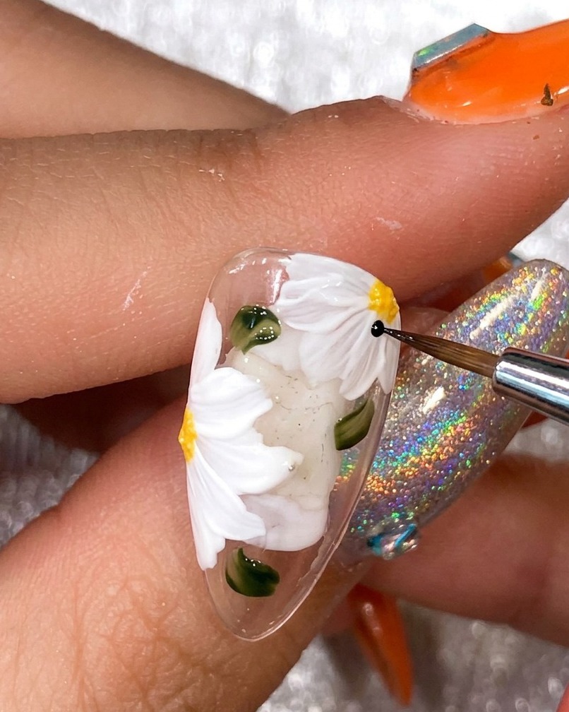 黒いライナーブラシで白い花びらの輪郭をなぞっている様子。