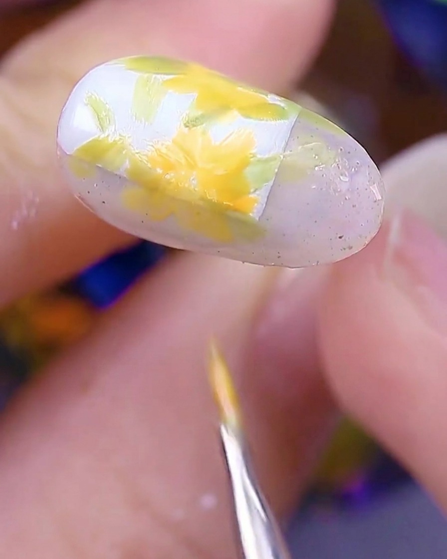 爪全体に花が描かれ、最後の花びらをブラシで仕上げている様子。