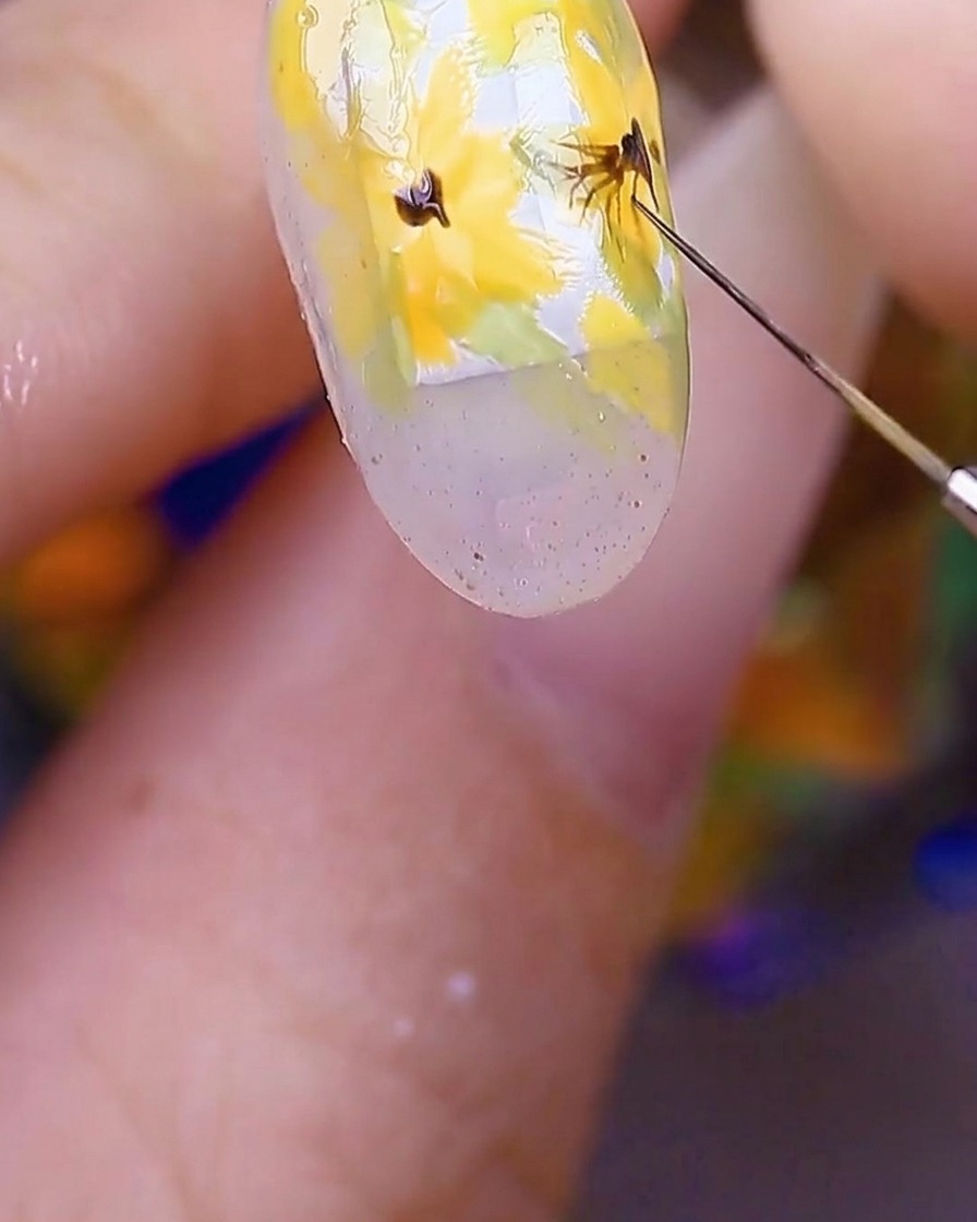 花の中心から外側へ、細いブラウンのラインを繊細に描き加えている様子。