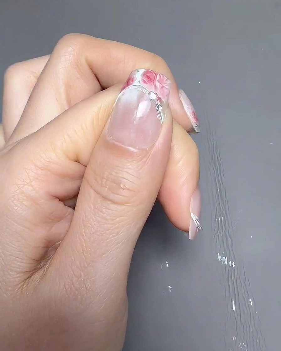 ピンセットを使い、爪先に少し広めのフレンチガイドシールを貼っている様子。