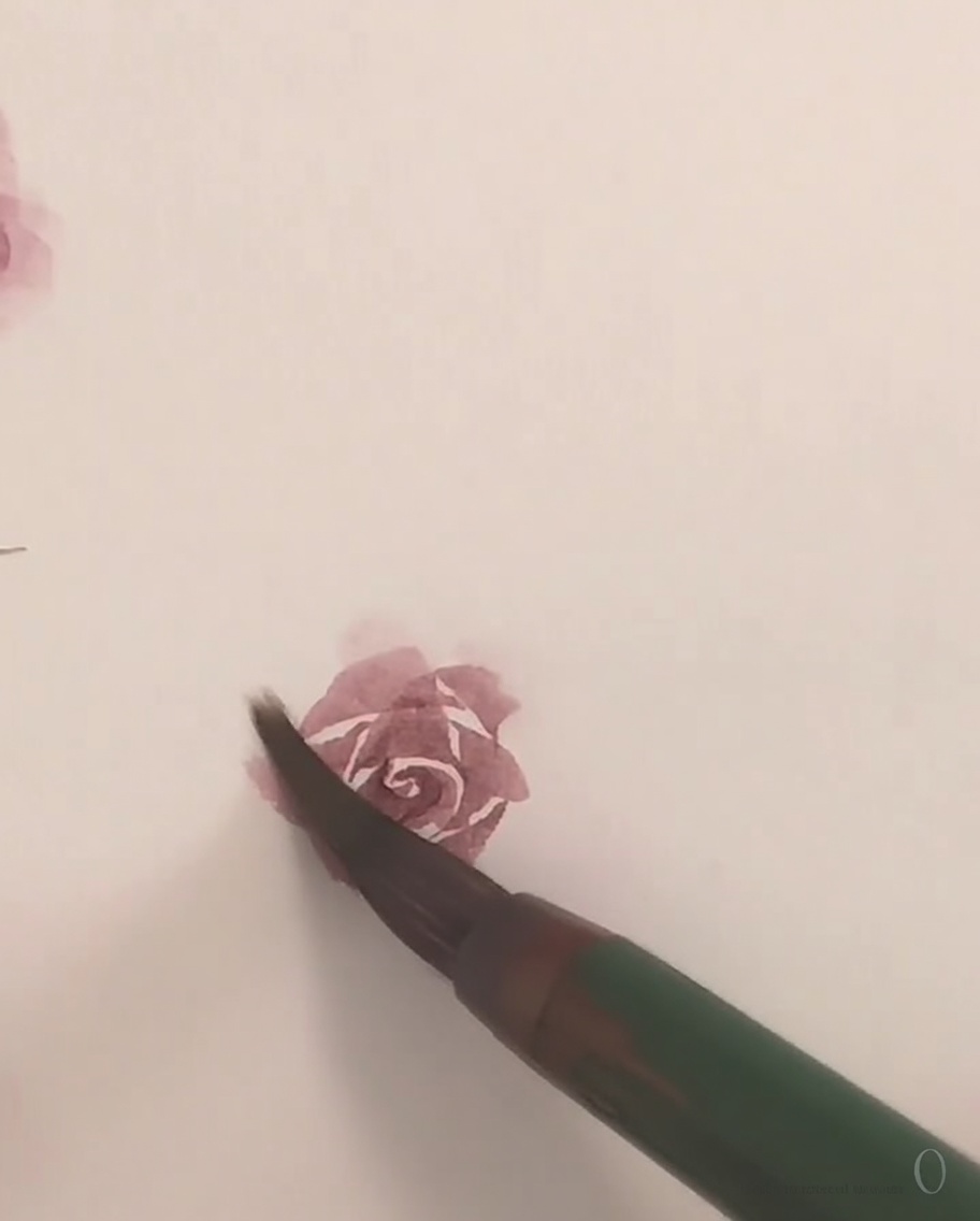 小さな筆を使って、バラの最後の外側の花びらを形成するための淡いピンクの水彩絵具を塗っている様子。