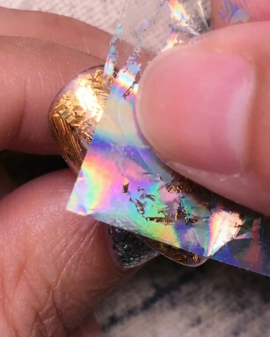 ネイルの隙間にホログラムシルバーのフォイルを押し付けている様子