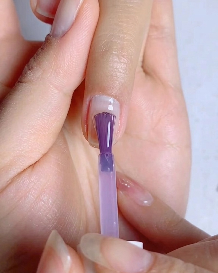 爪の表面に薄く均一にブルーパープルのカラージェルを塗っている様子。