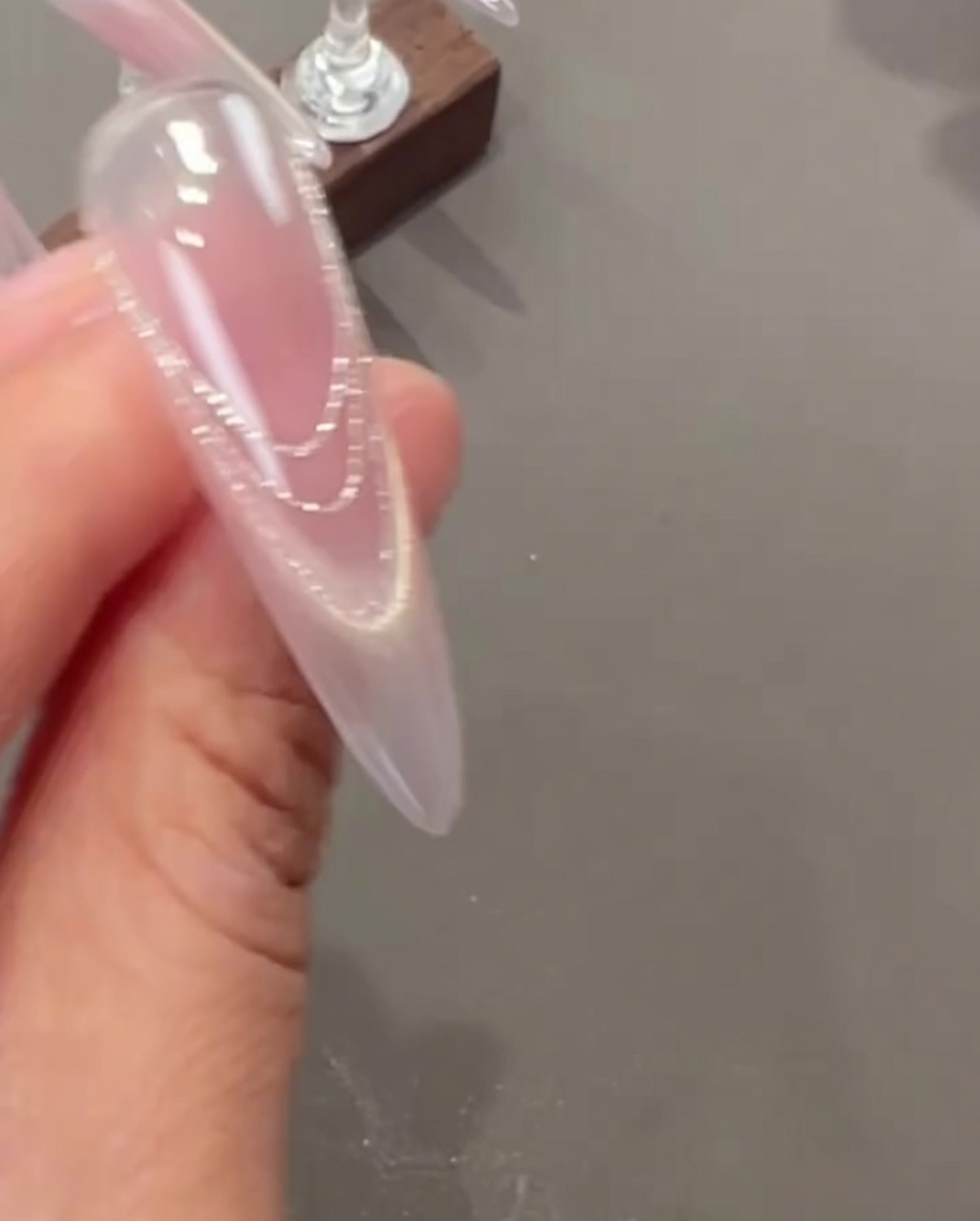 ピンセットで押し花と小さなパールチャームをネイルに乗せている様子。