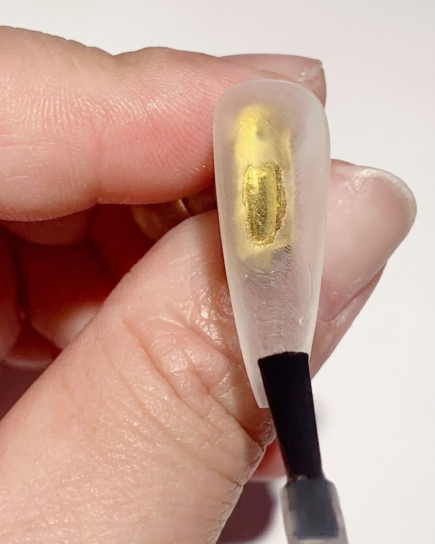 クリアネイルチップの内側に、クリアジェルベースコートを薄く塗布している様子。