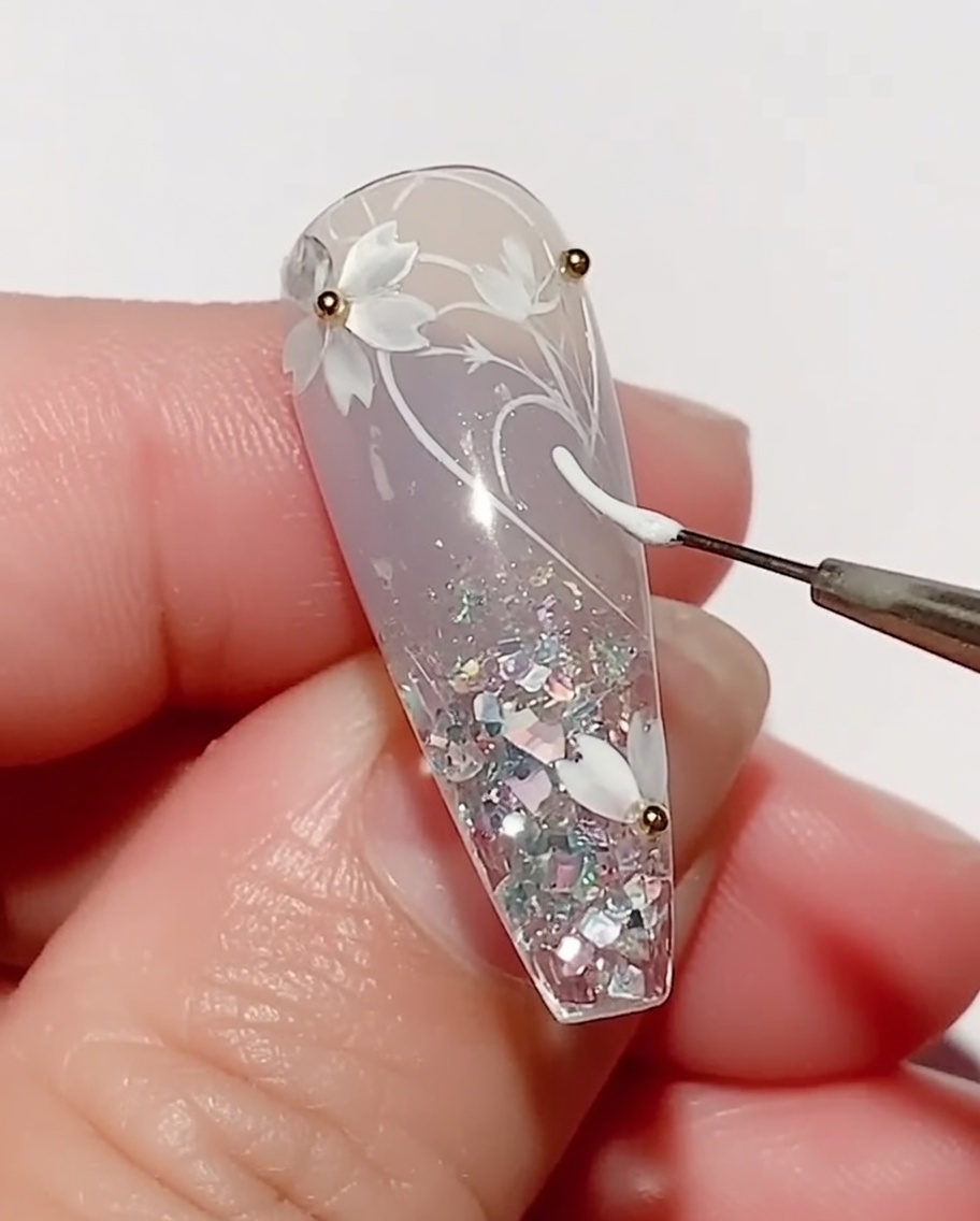 細いライナーブラシを使って、桜の横にホワイトジェルで葉を描いている様子。