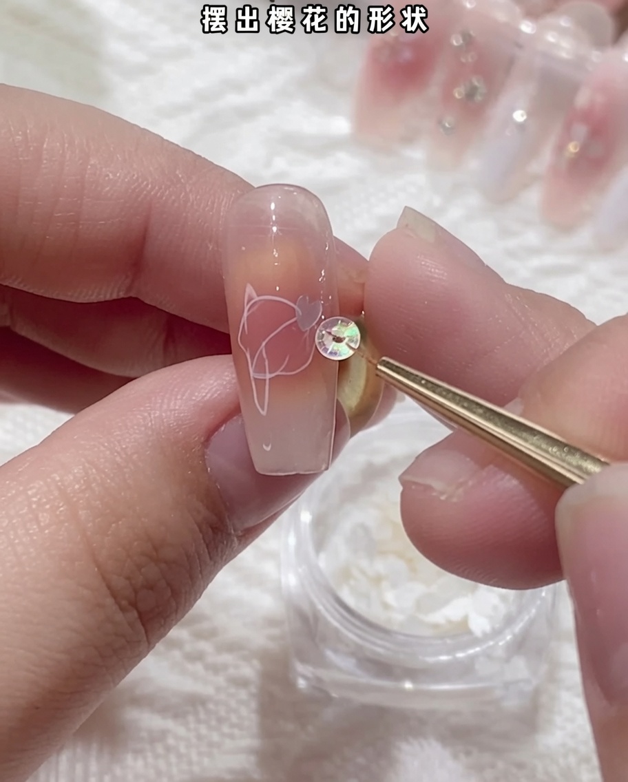 ピンセットで桜型のスパンコールを掴み、爪の上に配置している様子