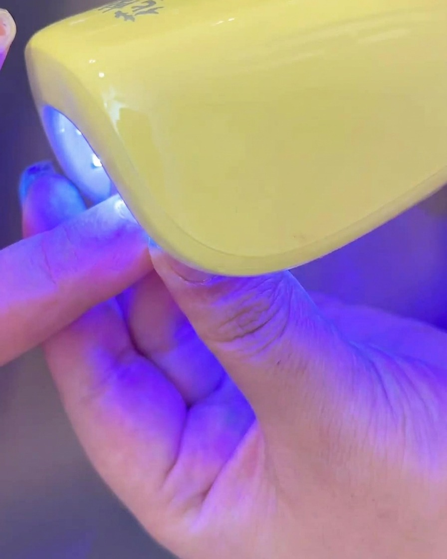 ミルキーホワイトジェルを塗った指をUV/LEDライトに入れている様子