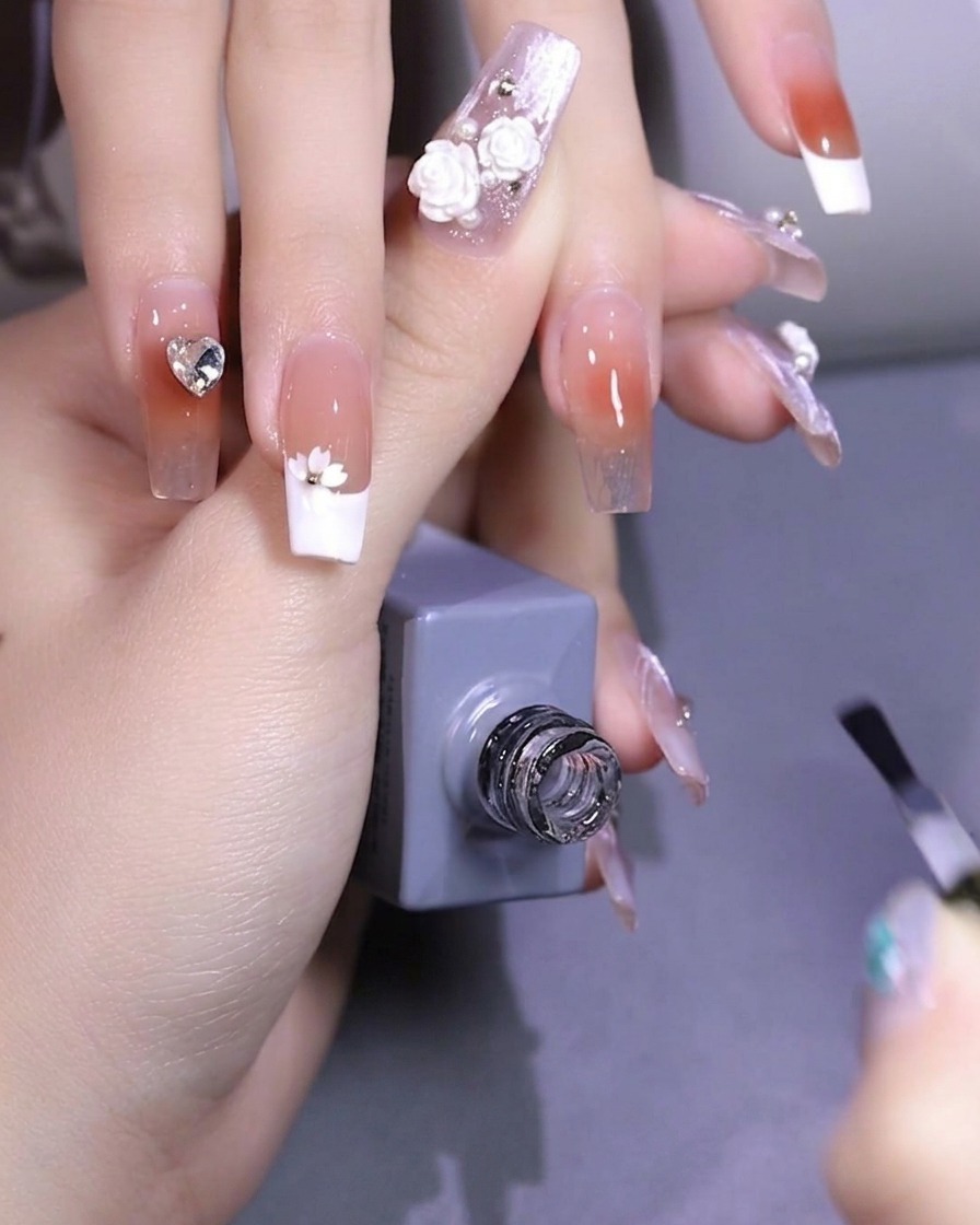 ピンセットで桜の花びら型スパンコールを爪の上に置いている様子。
