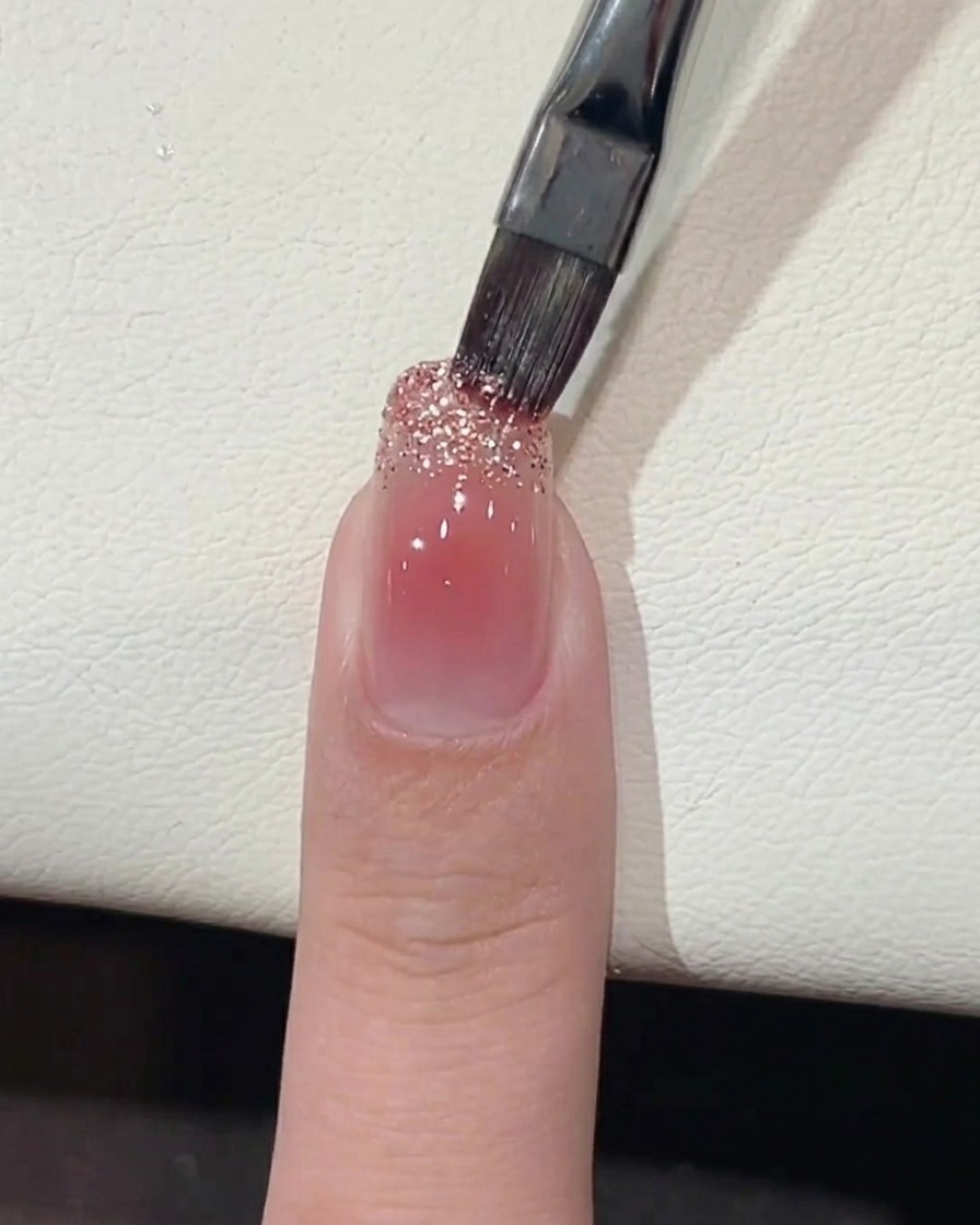 ネイルブラシで爪先にラメジェルを塗布している様子