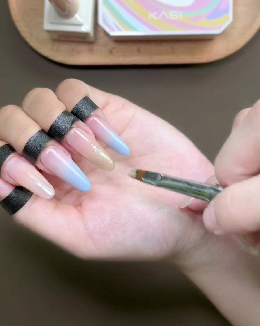 爪先に煌めくシャンパンカラーのキャッツアイジェルを平筆で塗布している様子。
