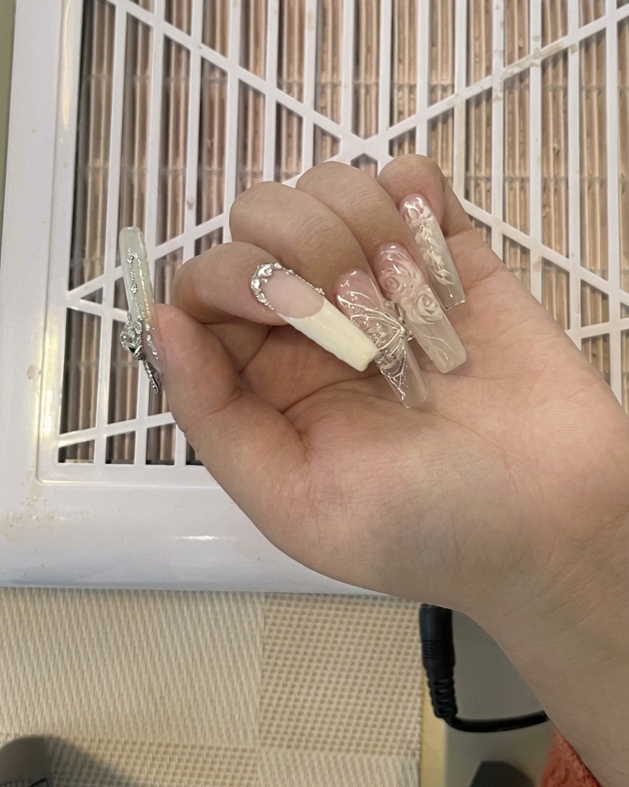 長く装飾されたネイルエクステンションを爪切りでカットしている様子。