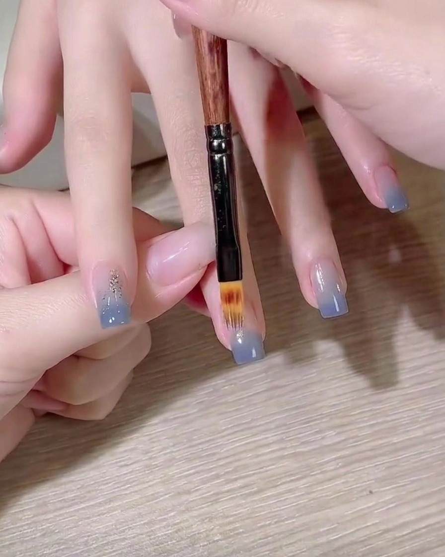 平筆を使って、爪の上でブルーのグラデーションを作っている様子。