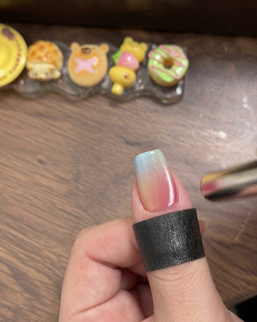 完成したカラフルなグラデーションネイルにクリアのトップコートを塗っている様子
