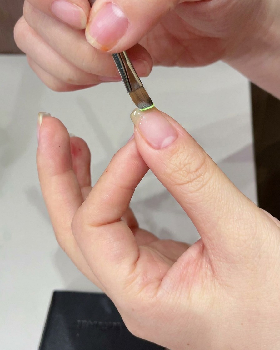 自爪の先端に細筆でライトグリーンジェルを塗っている様子