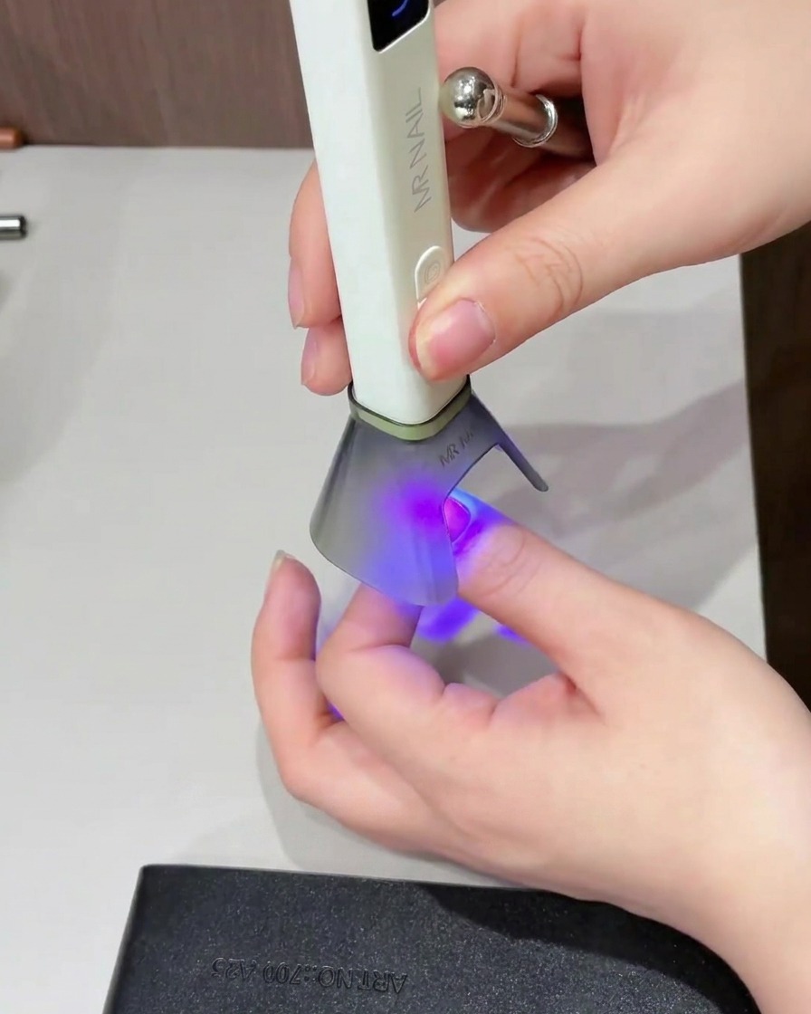 爪全体に輝きのあるトップコートを塗っている様子