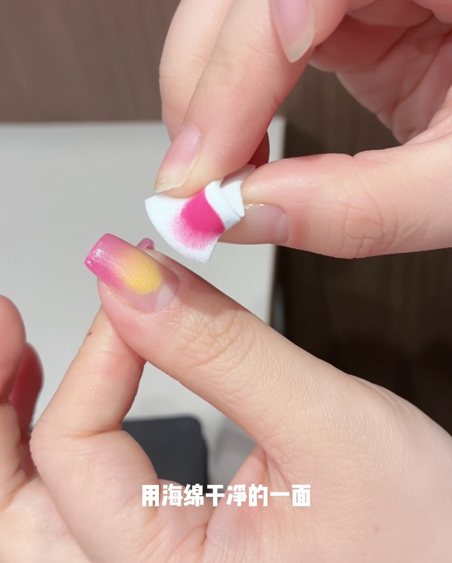 新しいスポンジを使って、爪の上のイエローのジェルを優しく叩き、花びらのような形にぼかしている様子。